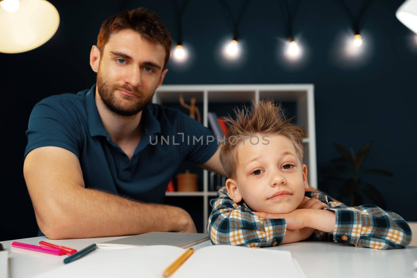 Dad and son doing school homework together sitting at the table
