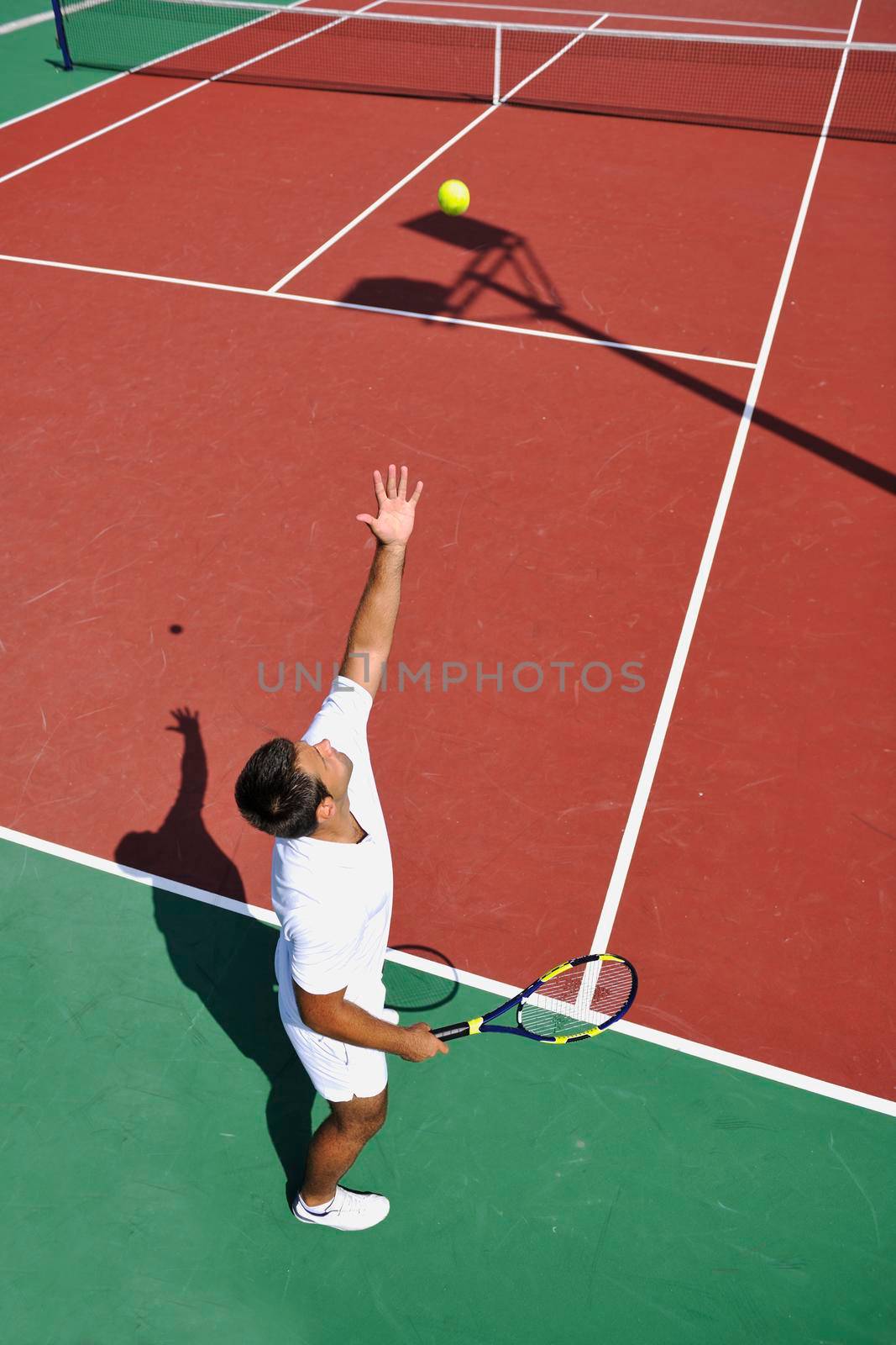 young man play tennis outdoor by dotshock