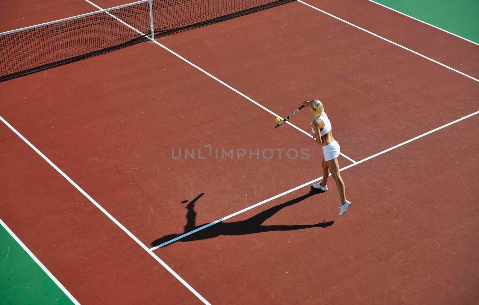 young woman play tennis outdoor by dotshock
