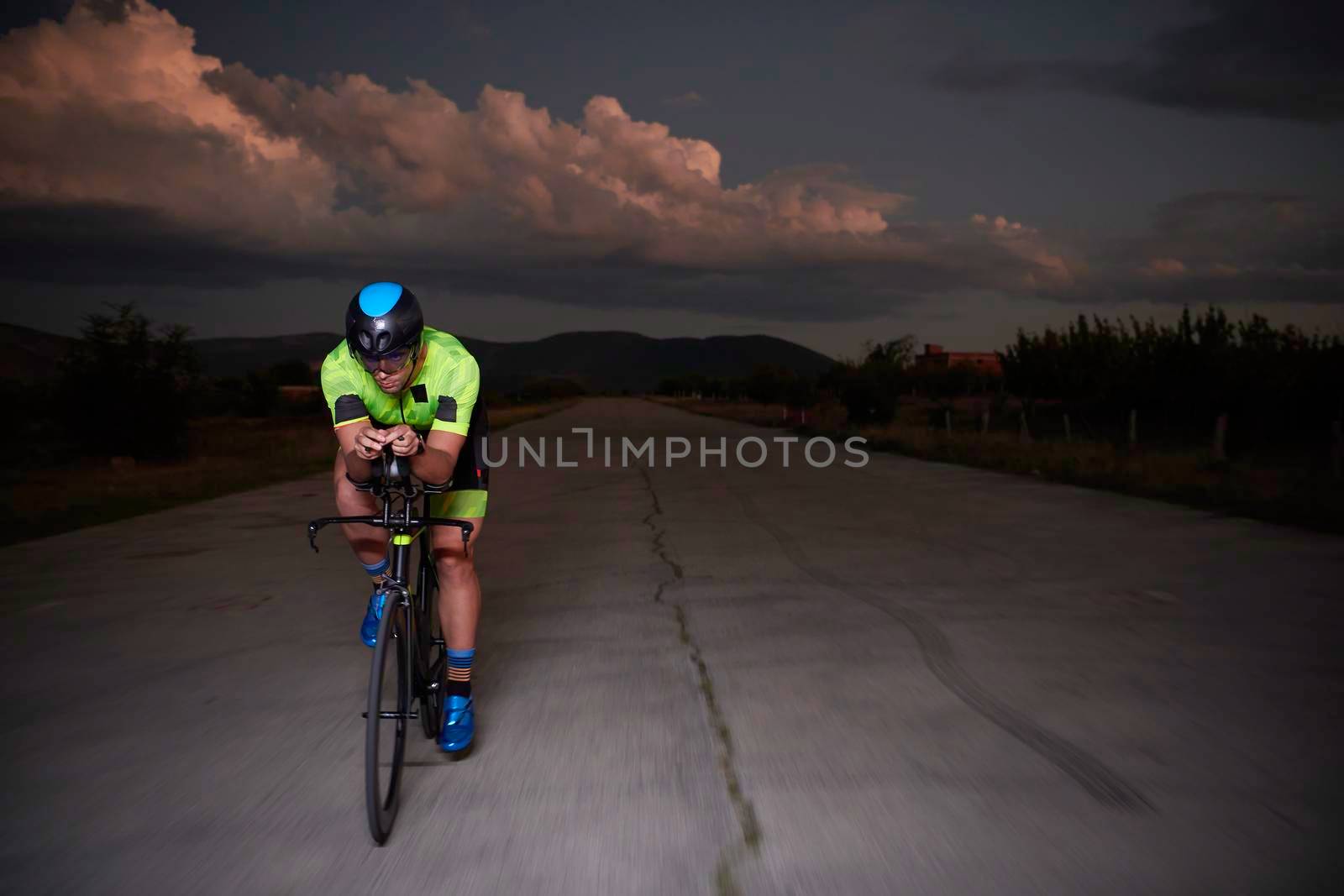 triathlon athlete riding bike fast  at night by dotshock