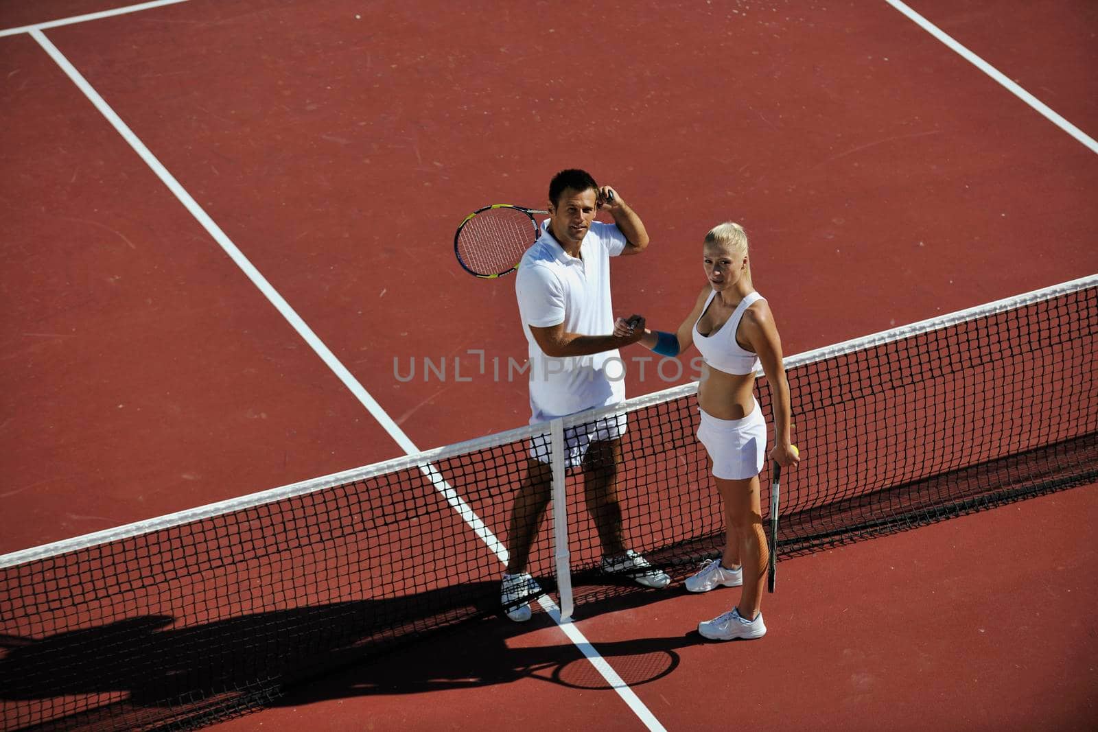 happy young couple play tennis game outdoor man and woman