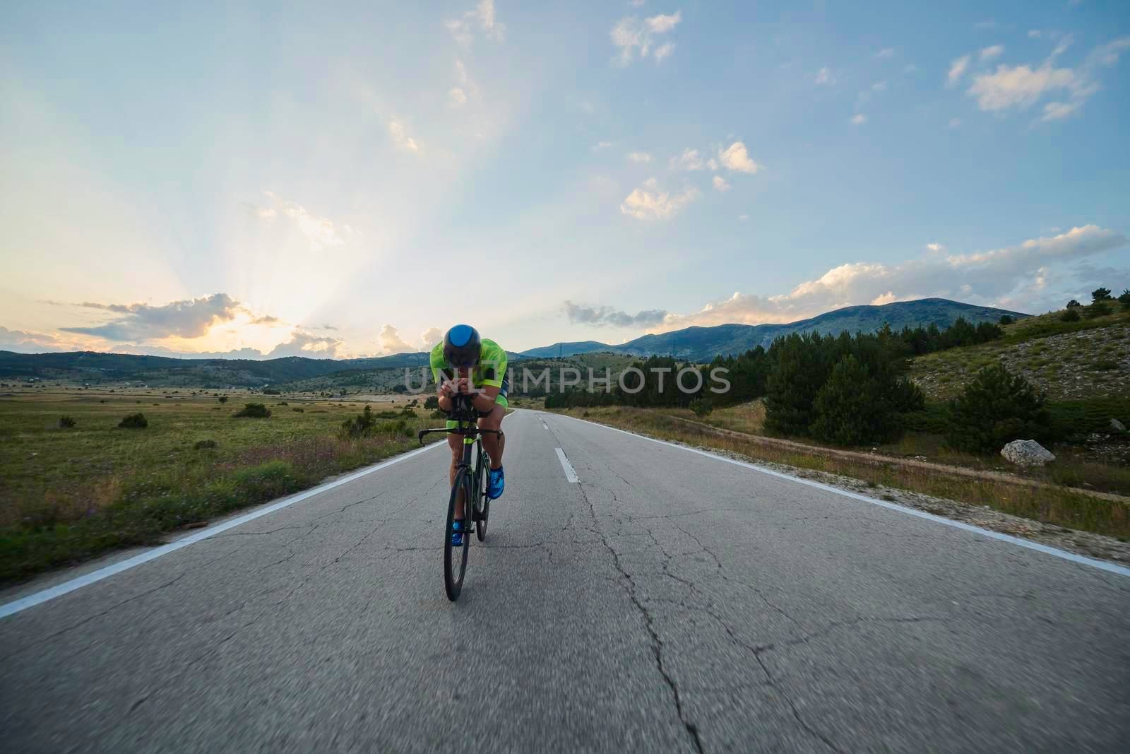 triathlon athlete riding professional racing bike at workout on curvy country road