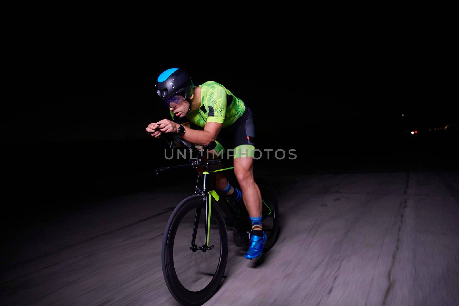 triathlon athlete riding bike fast  at night by dotshock