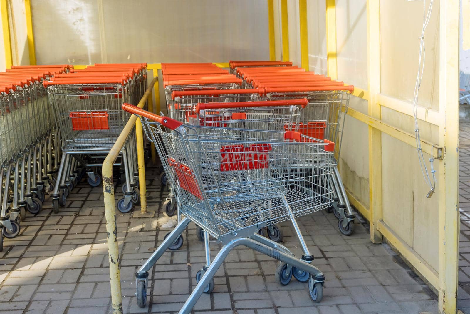A row of metal shopping carts near a shopping center are placed in a row in a hypermarket the store