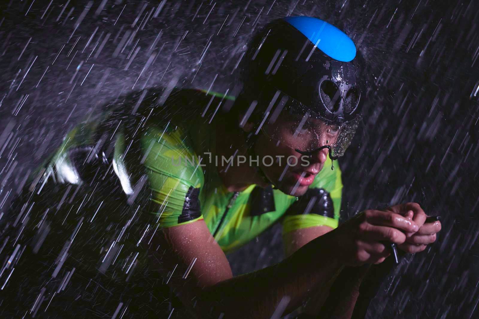 triathlon athlete riding bike  fast on rainy night by dotshock