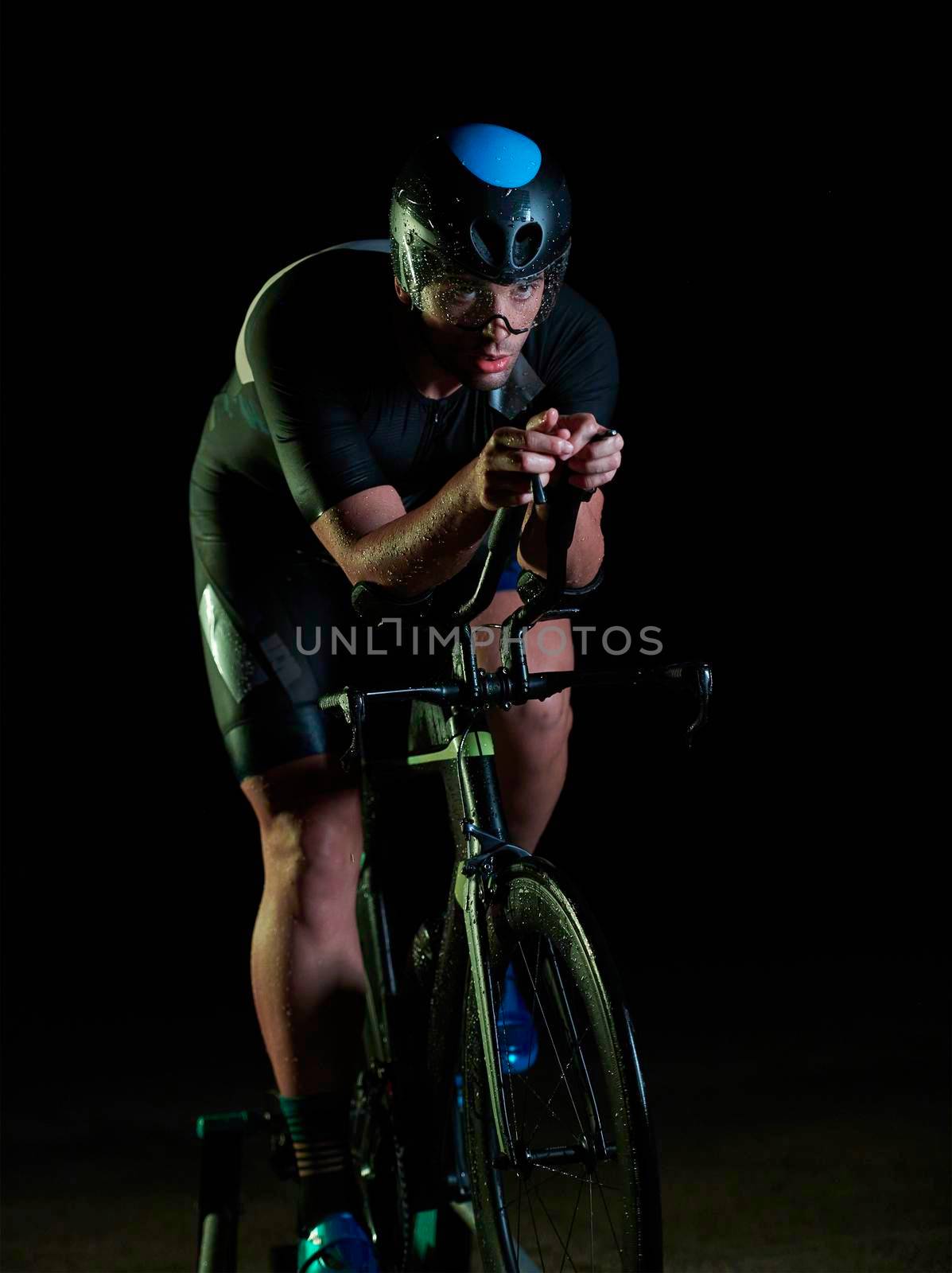 triathlon athlete riding bike fast at night by dotshock