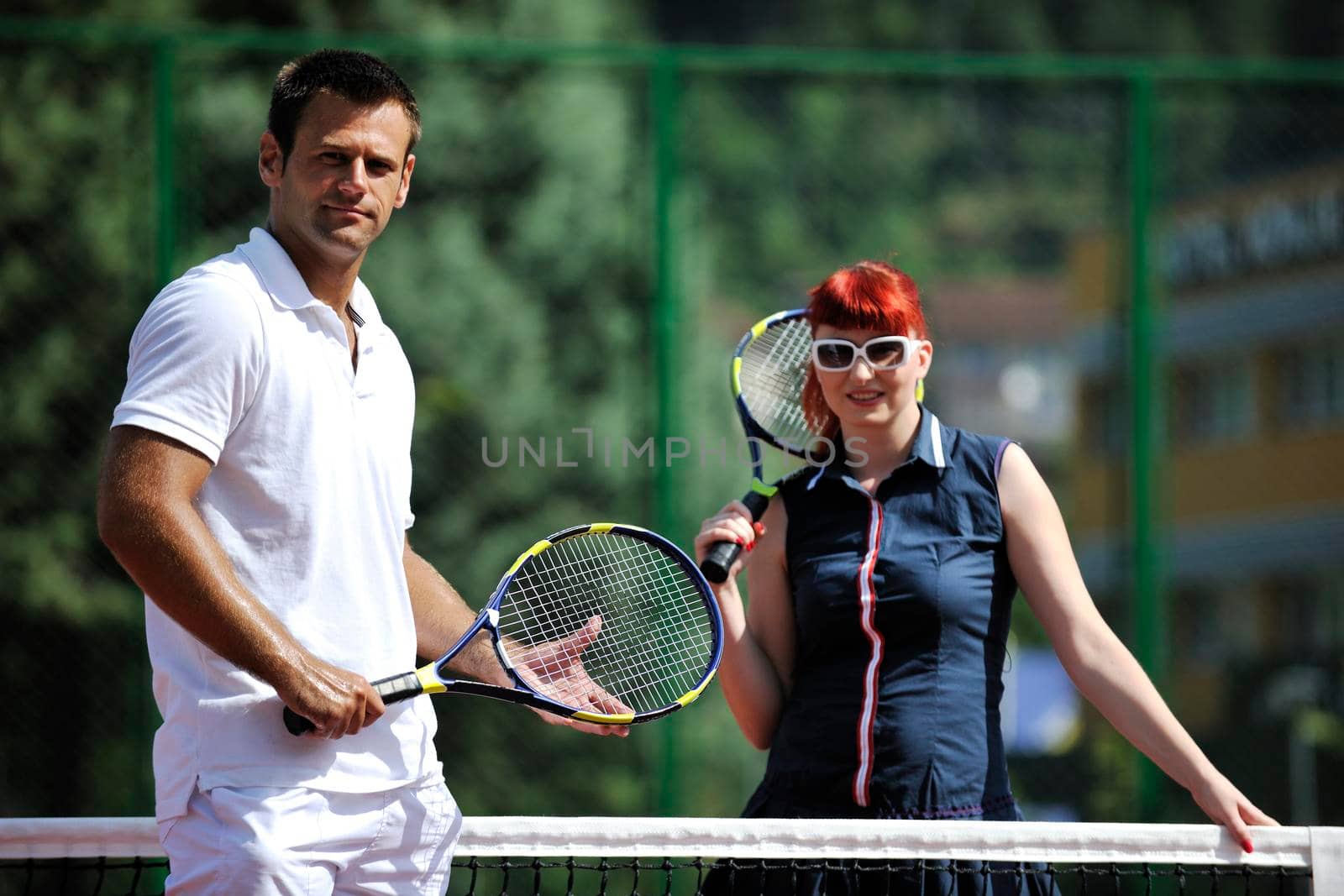 happy young couple play tennis game outdoor by dotshock