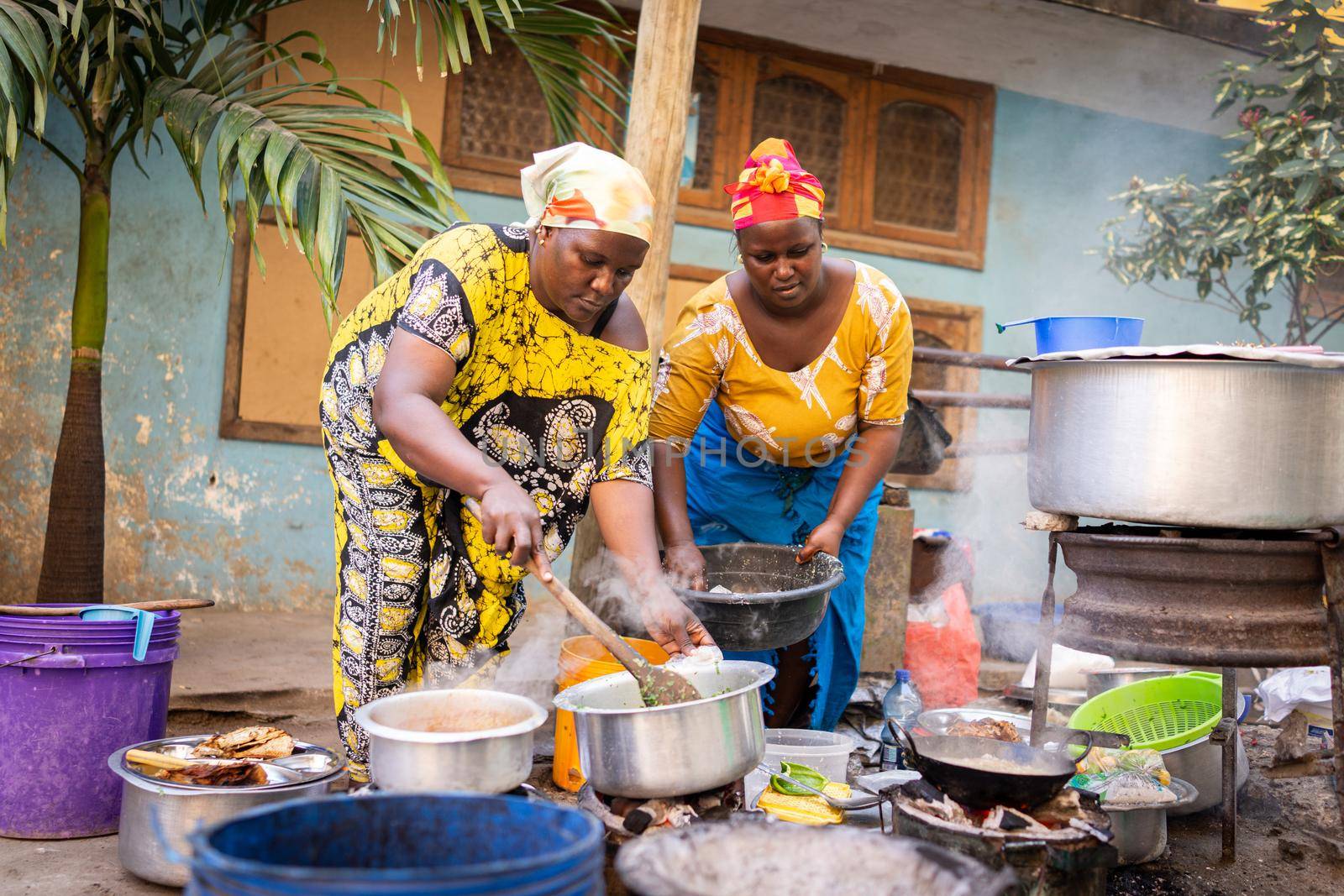 African woman cooking traditional food on street by Zurijeta