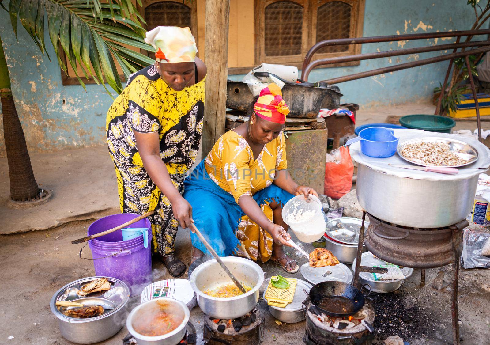 African woman cooking traditional food on street by Zurijeta