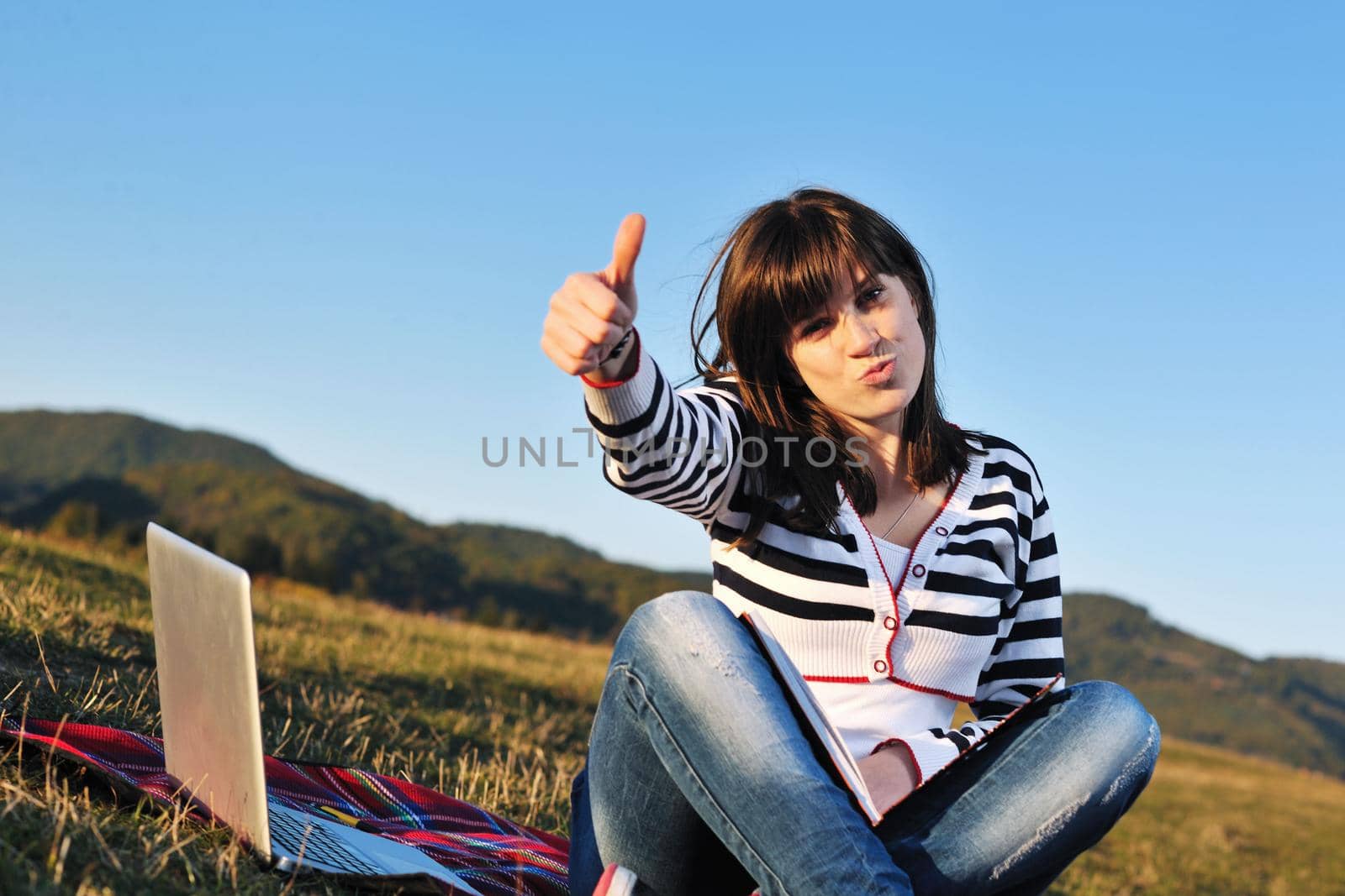 young teen girl read book and study homework outdoor in nature with blue sky in background