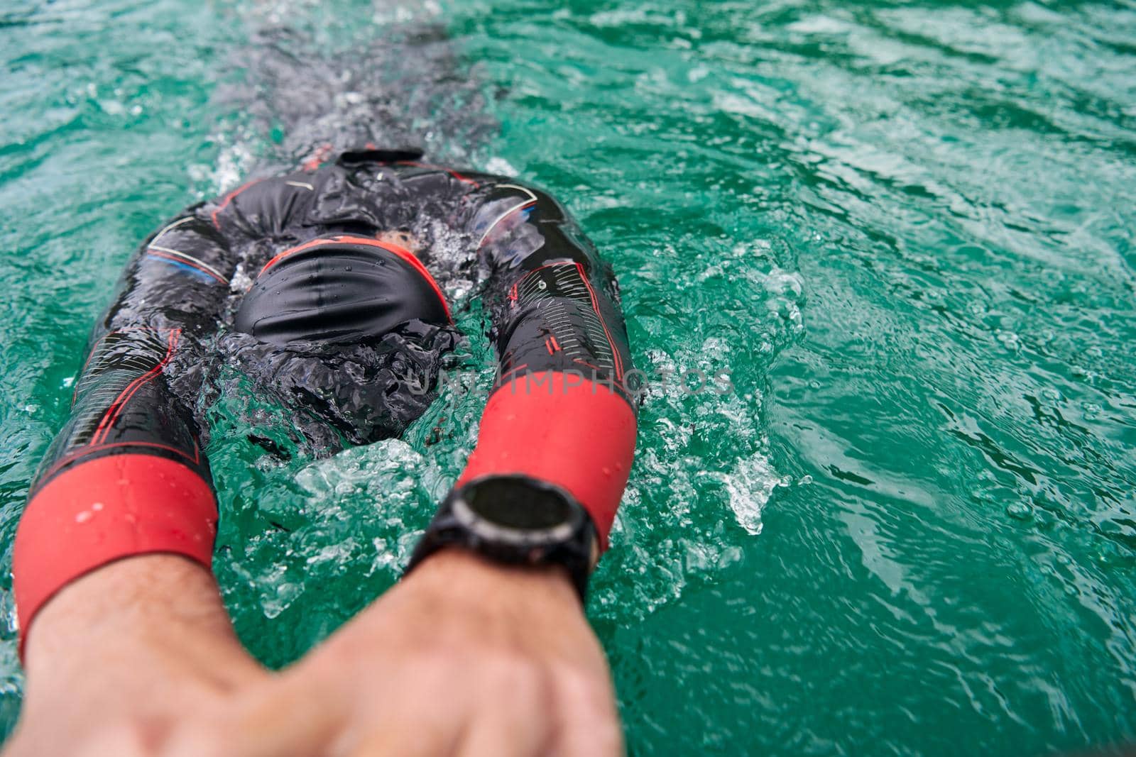 triathlon athlete swimming on extreme morning training in green lake wearing wetsuit