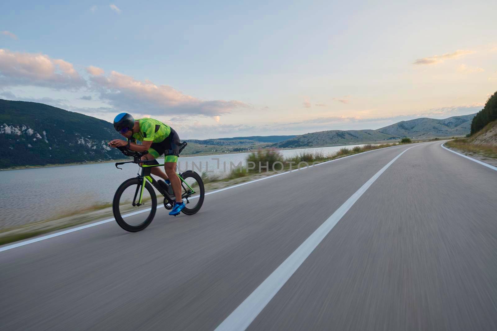 triathlon athlete riding professional racing bike at workout on curvy country road