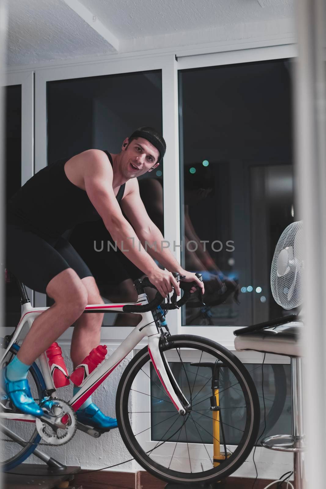 Man cycling on the machine trainer he is exercising in the home at night playing online bike racing game by dotshock