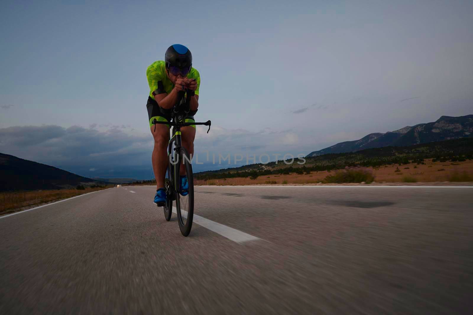 triathlon athlete riding professional racing bike at workout on curvy country road