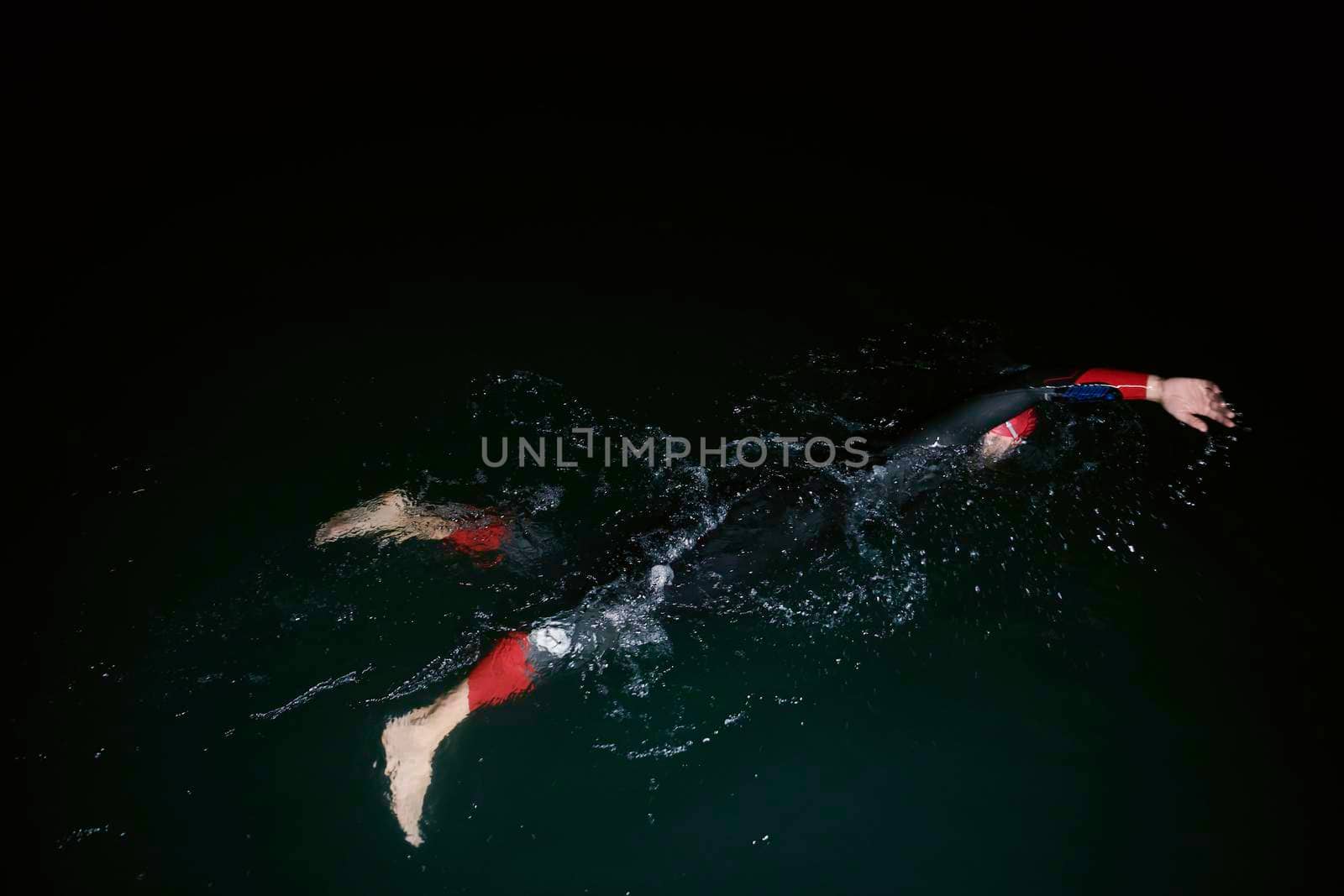 triathlon swimmer have extreme training  on dark night wearing wetsuit concept of strength and endurance