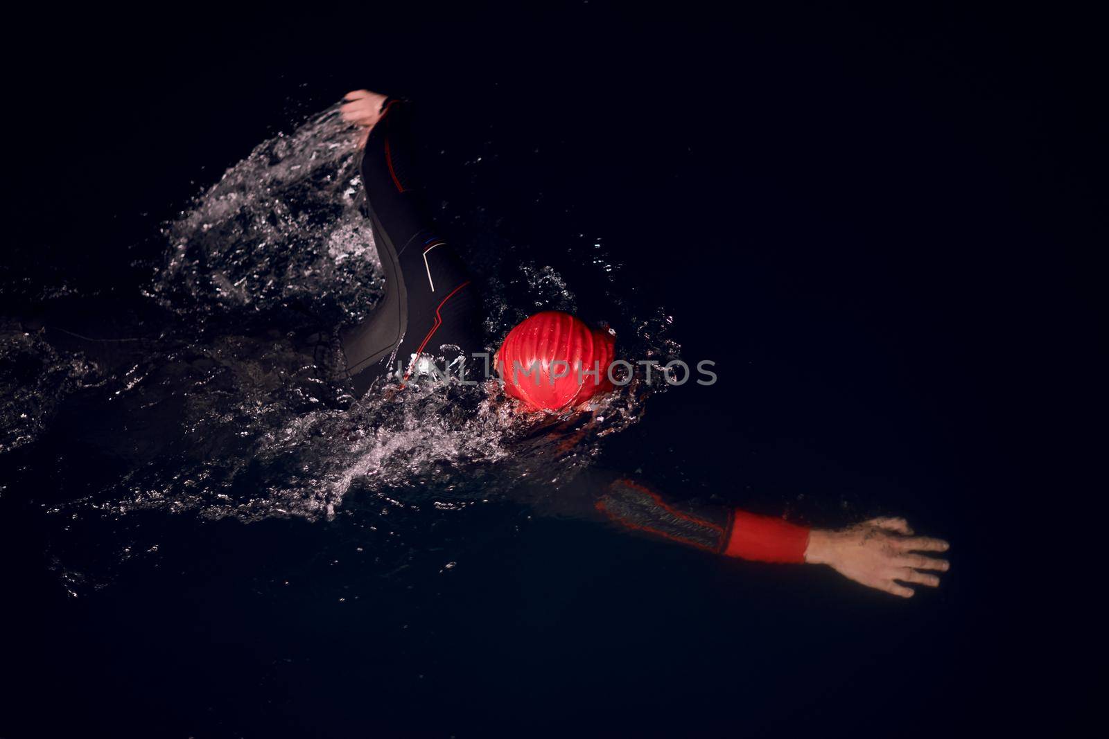 triathlon swimmer have extreme training  on dark night wearing wetsuit concept of strength and endurance