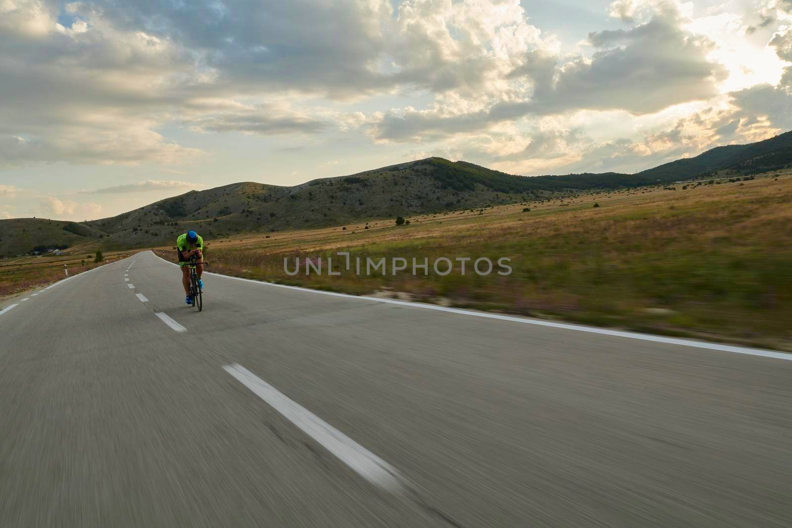 triathlon athlete riding professional racing bike at workout on curvy country road