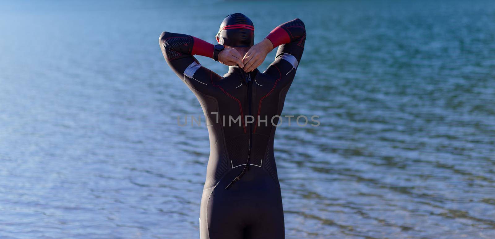 authentic triathlon athlete getting ready for swimming training on lake by dotshock