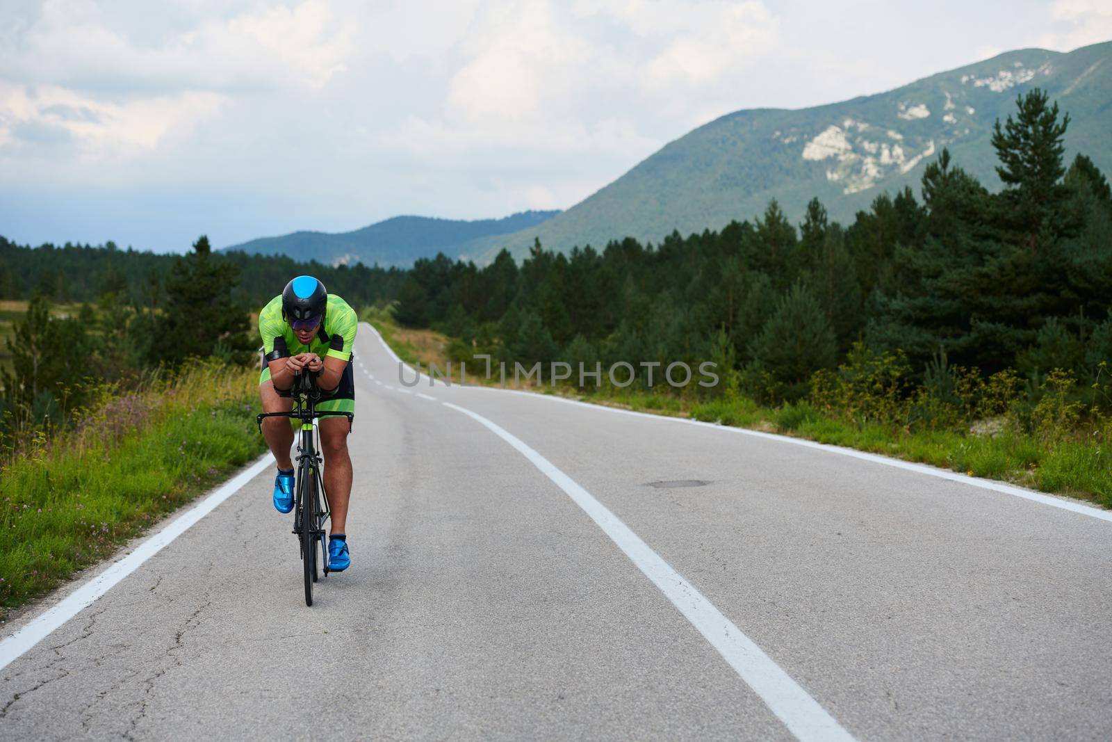 triathlon athlete riding professional racing bike at workout on curvy country road