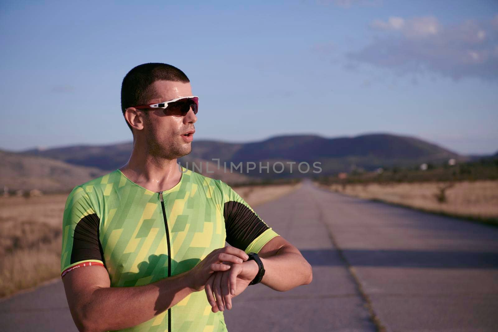 triathlon athlete running  on morning training seting smartwatch while resting