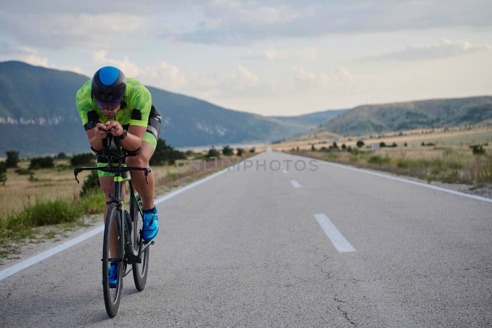 triathlon athlete riding professional racing bike at workout on curvy country road