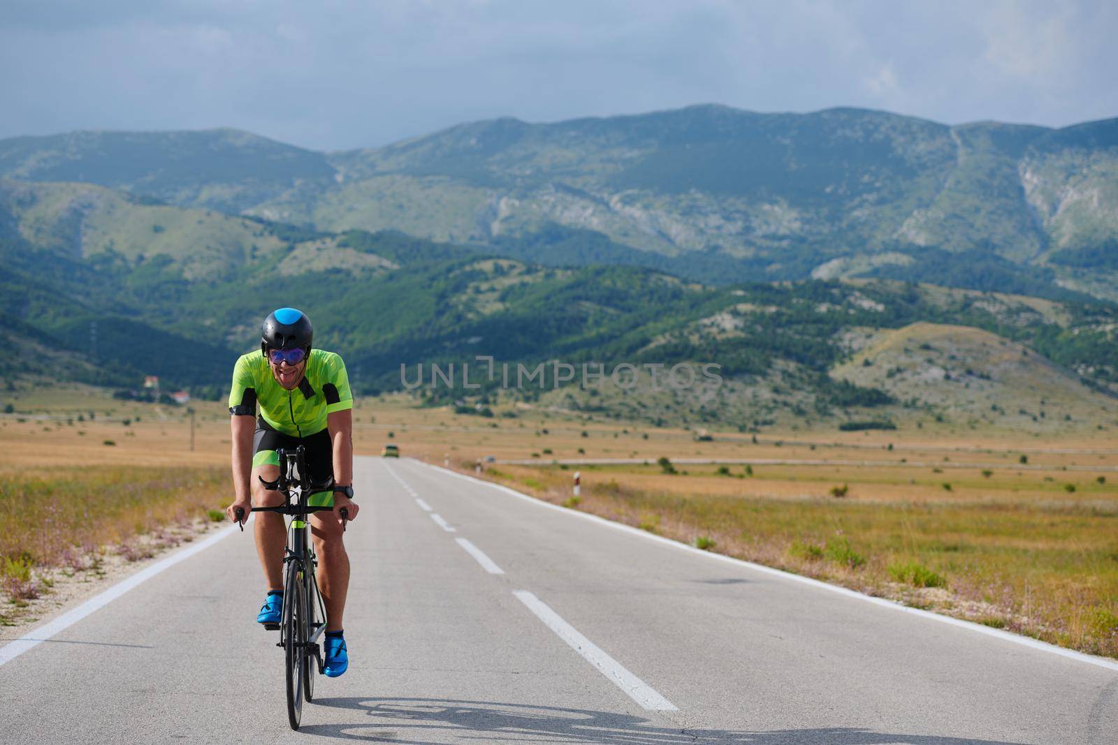 triathlon athlete riding professional racing bike at workout on curvy country road