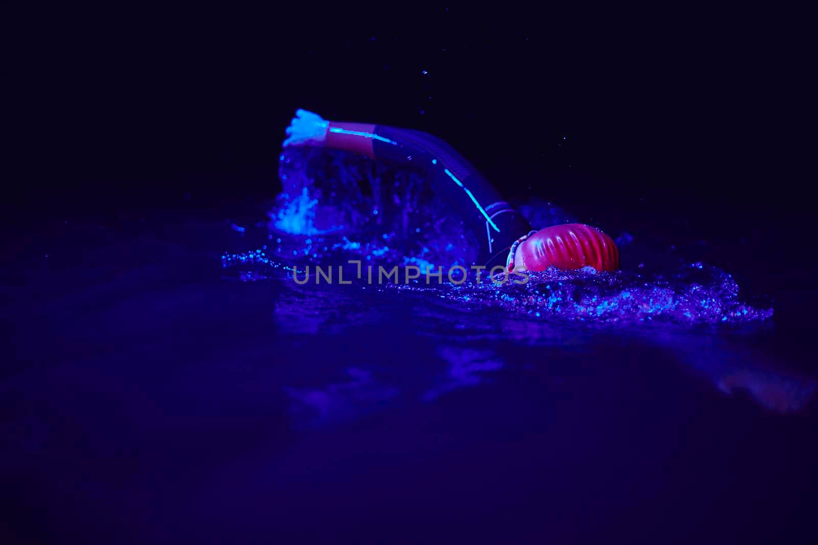 real triathlon athlete swimming in dark night by dotshock