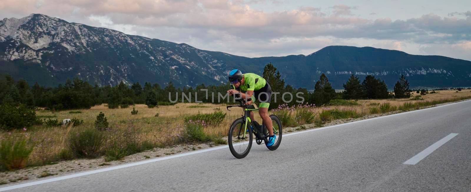 triathlon athlete riding professional racing bike at workout on curvy country road