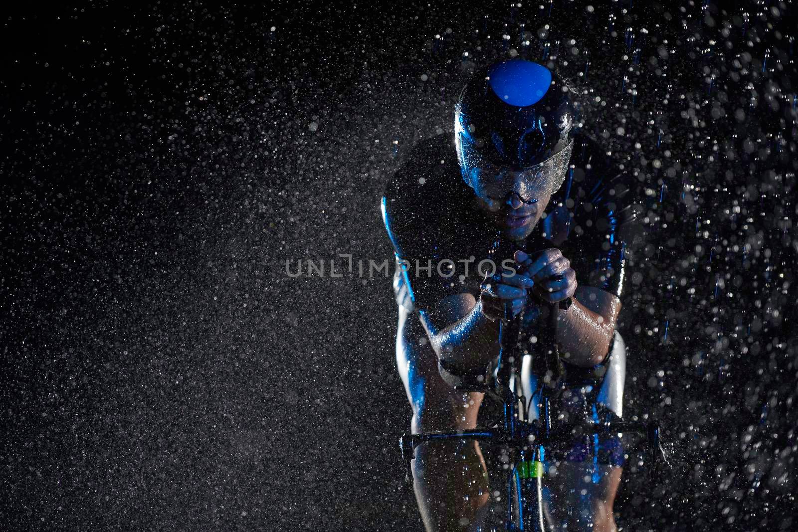 triathlon athlete riding bike  fast on rainy night by dotshock