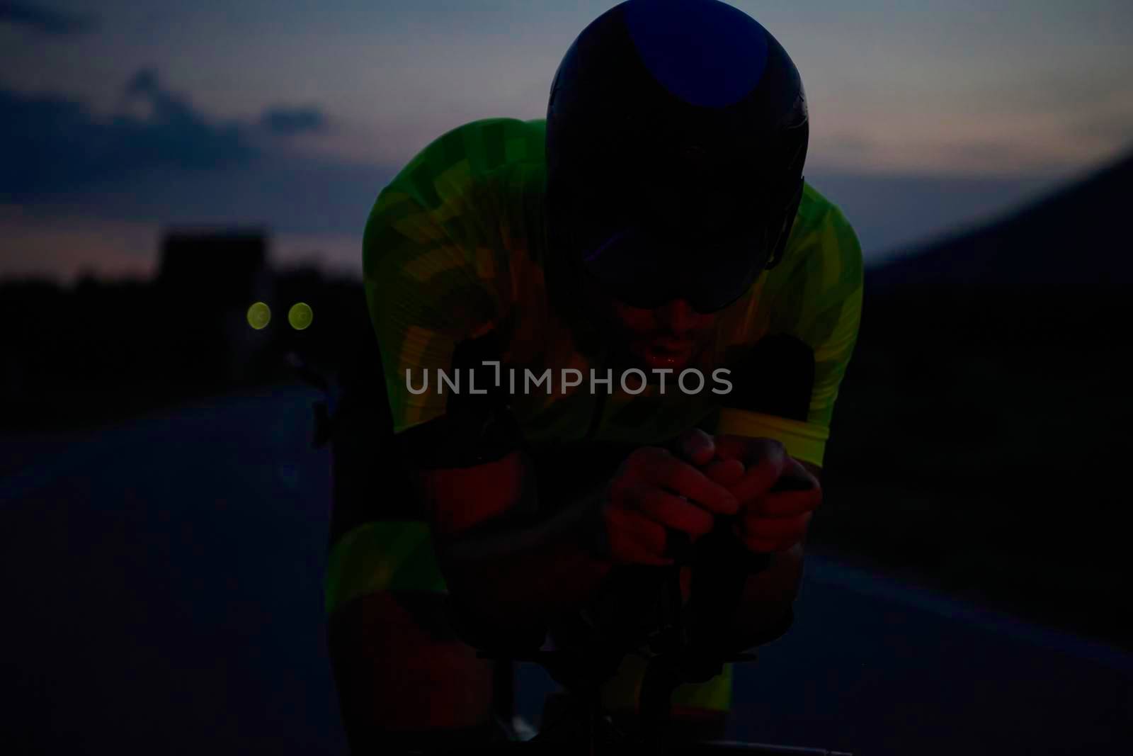 triathlon athlete riding professional racing bike at night workout on curvy country road w