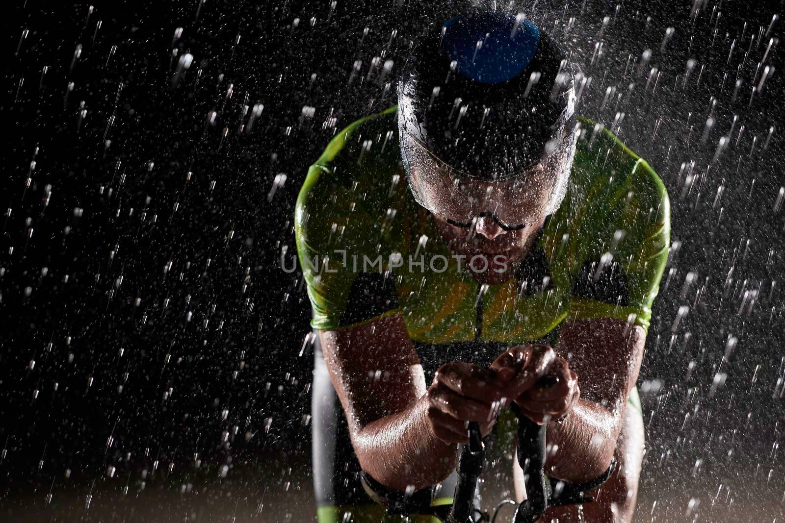 triathlon athlete riding professional racing bike fast  at night with bad weather and falling rain