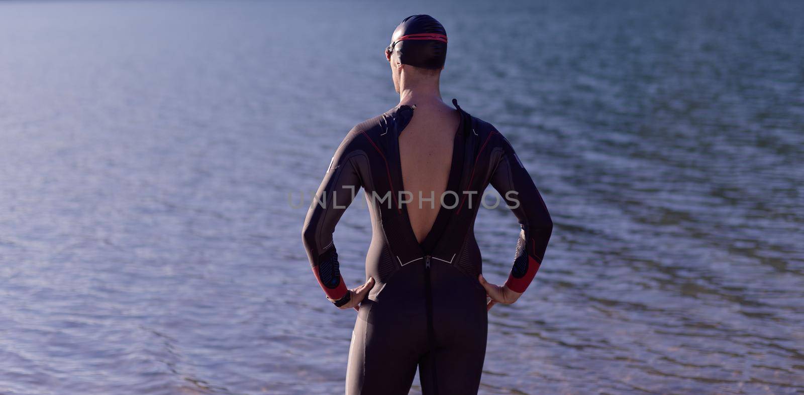 authentic triathlon athlete getting ready for swimming training on lake by dotshock