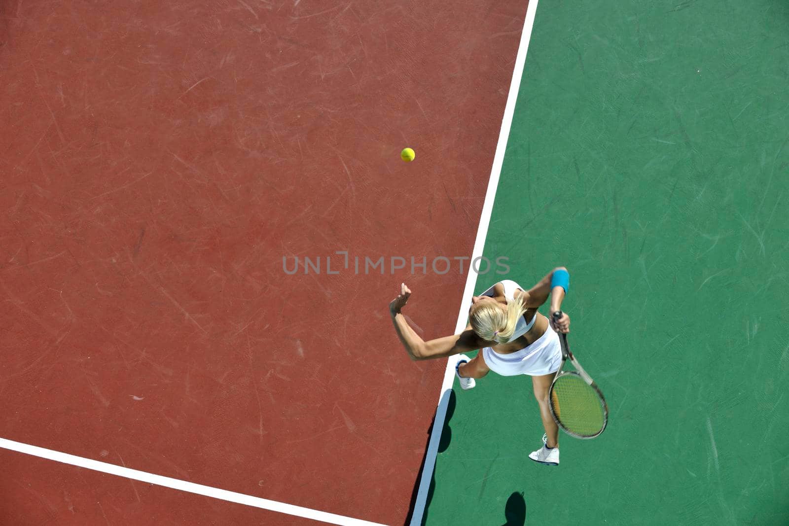 young fit woman play tennis outdoor on orange tennis field at early morning