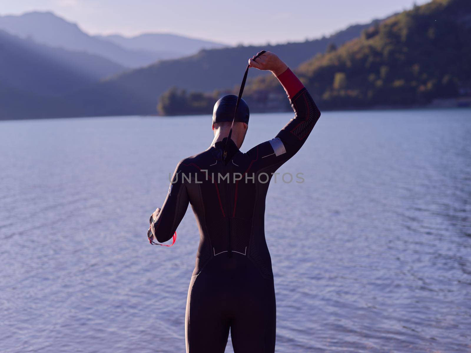 authentic triathlon athlete getting ready for swimming training on lake by dotshock