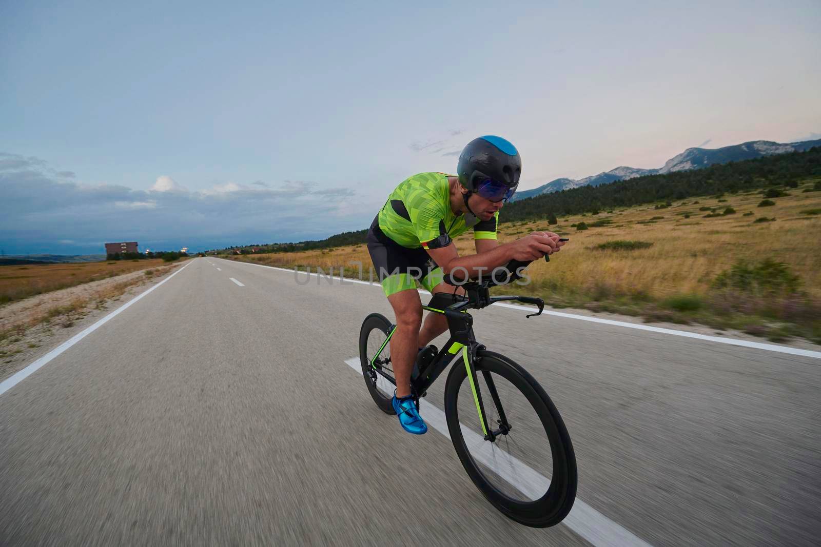 triathlon athlete riding professional racing bike at workout on curvy country road