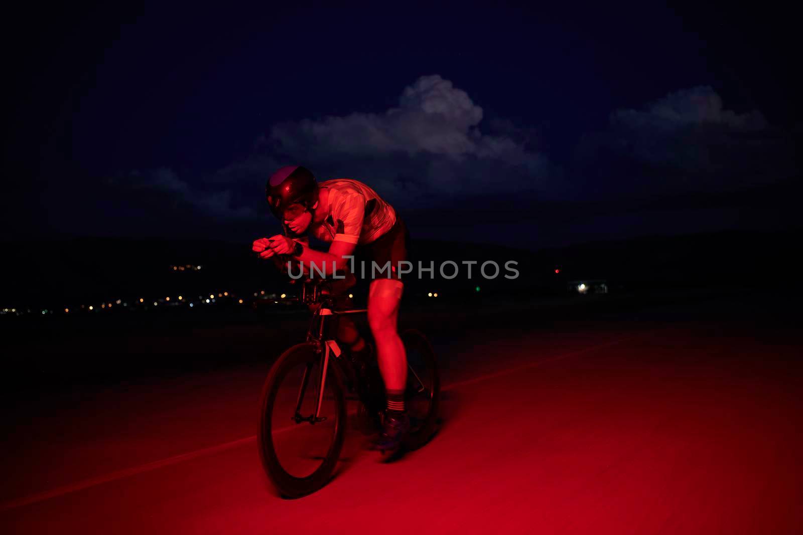 triathlon athlete cycling fast riding professional racing bike at night neon color gel lights