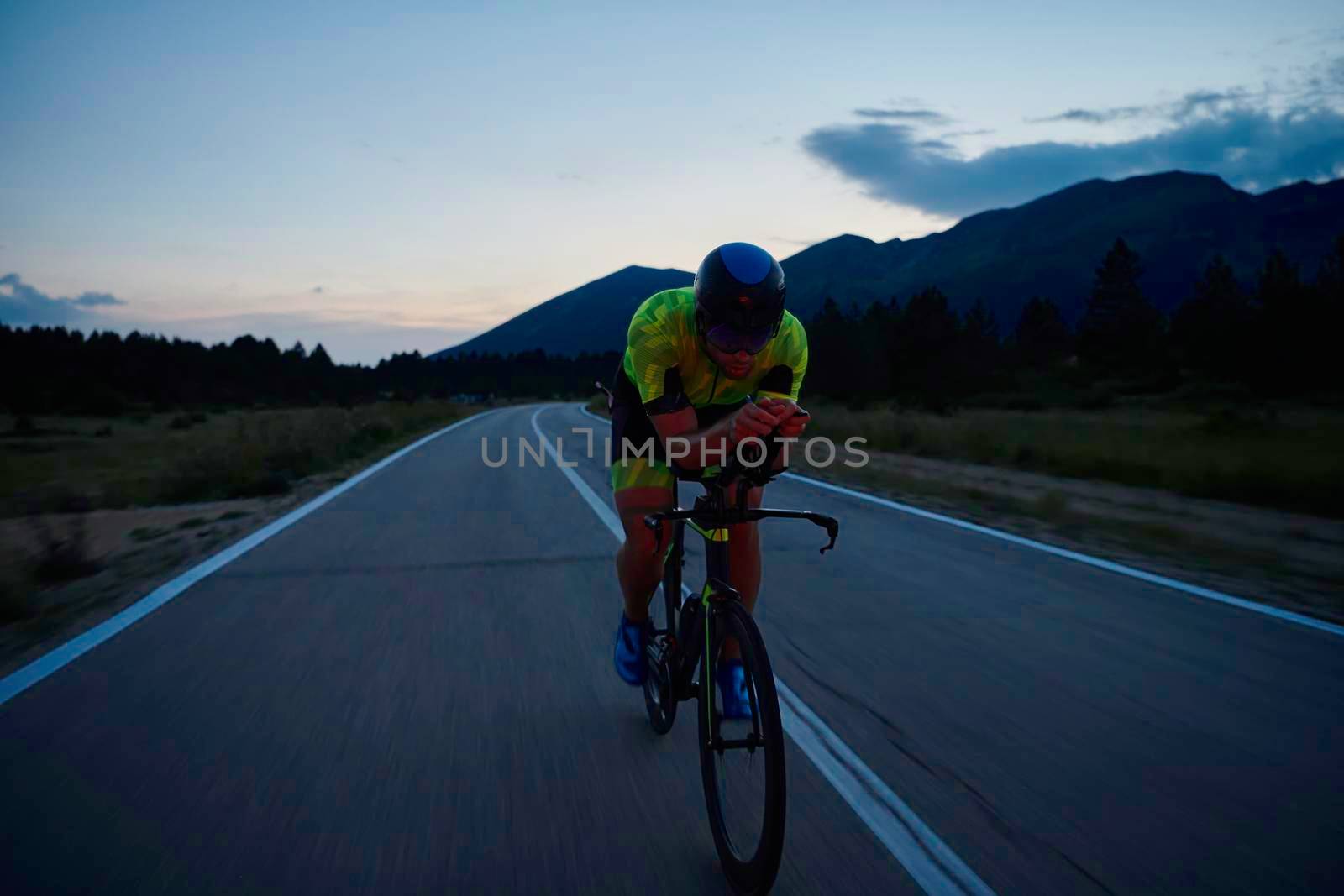 triathlon athlete riding professional racing bike at night workout on curvy country road w