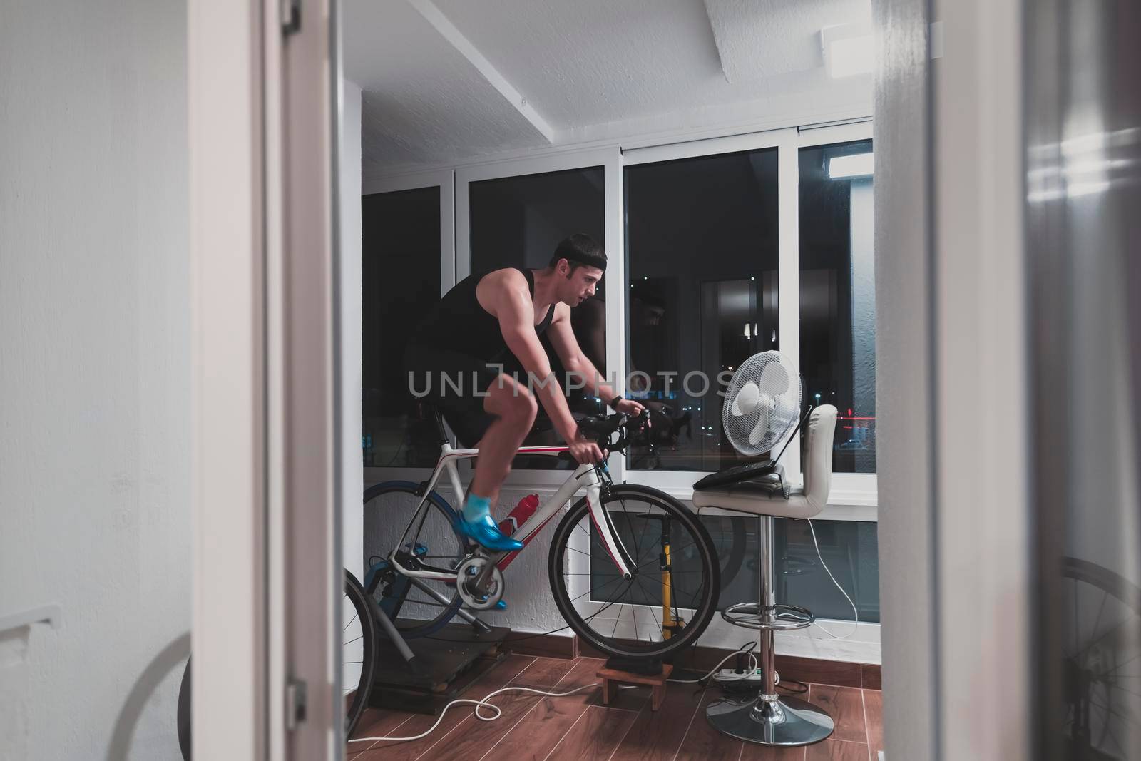 Man cycling on the machine trainer he is exercising in the home at night playing online bike racing game by dotshock