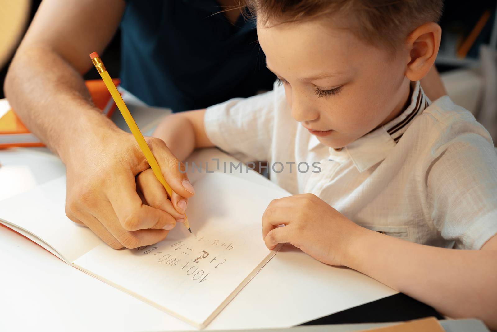 Little boy writing something in his notebook close up