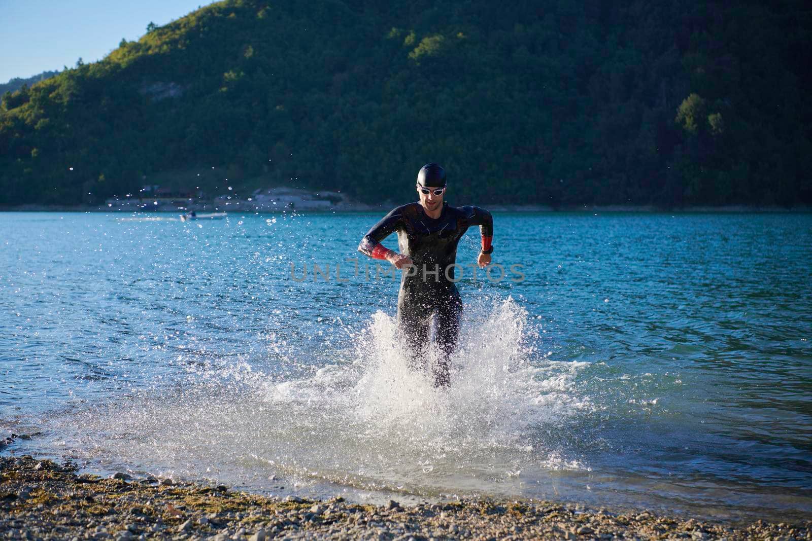 triathlon athlete starting swimming training on lake by dotshock