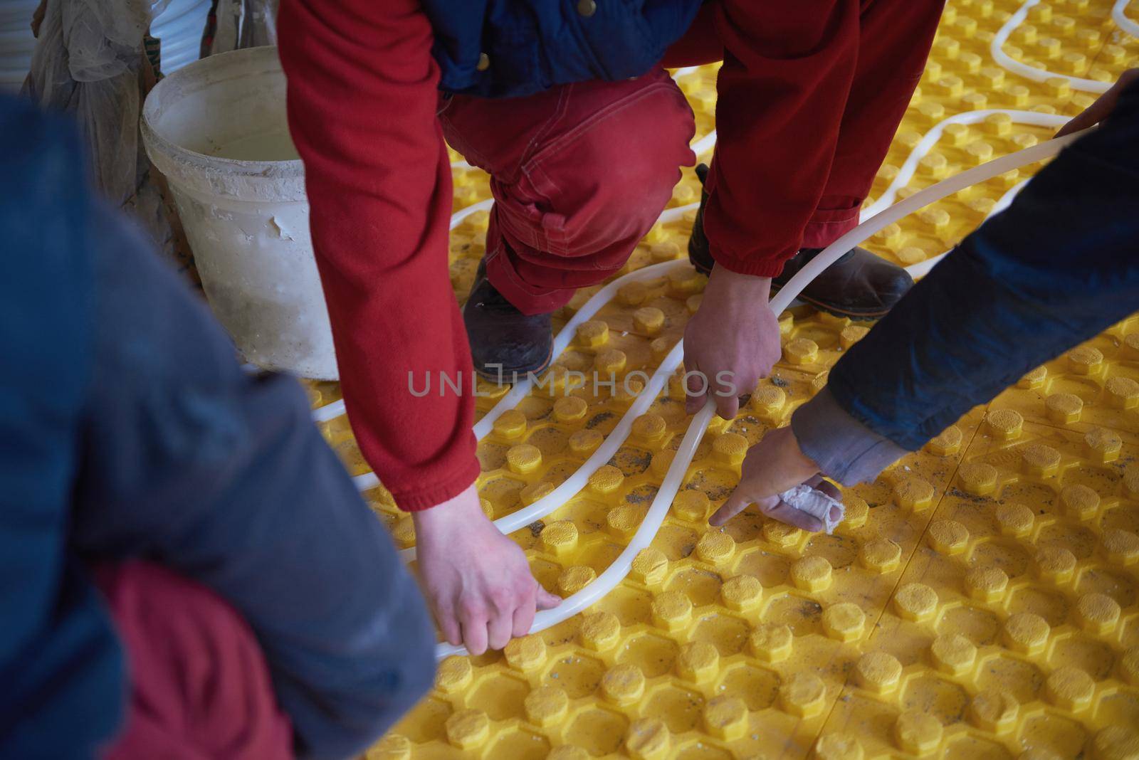 workers installing underfloor heating system by dotshock