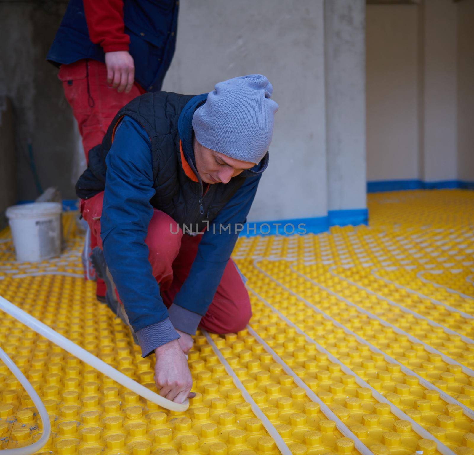 workers installing underfloor heating system by dotshock