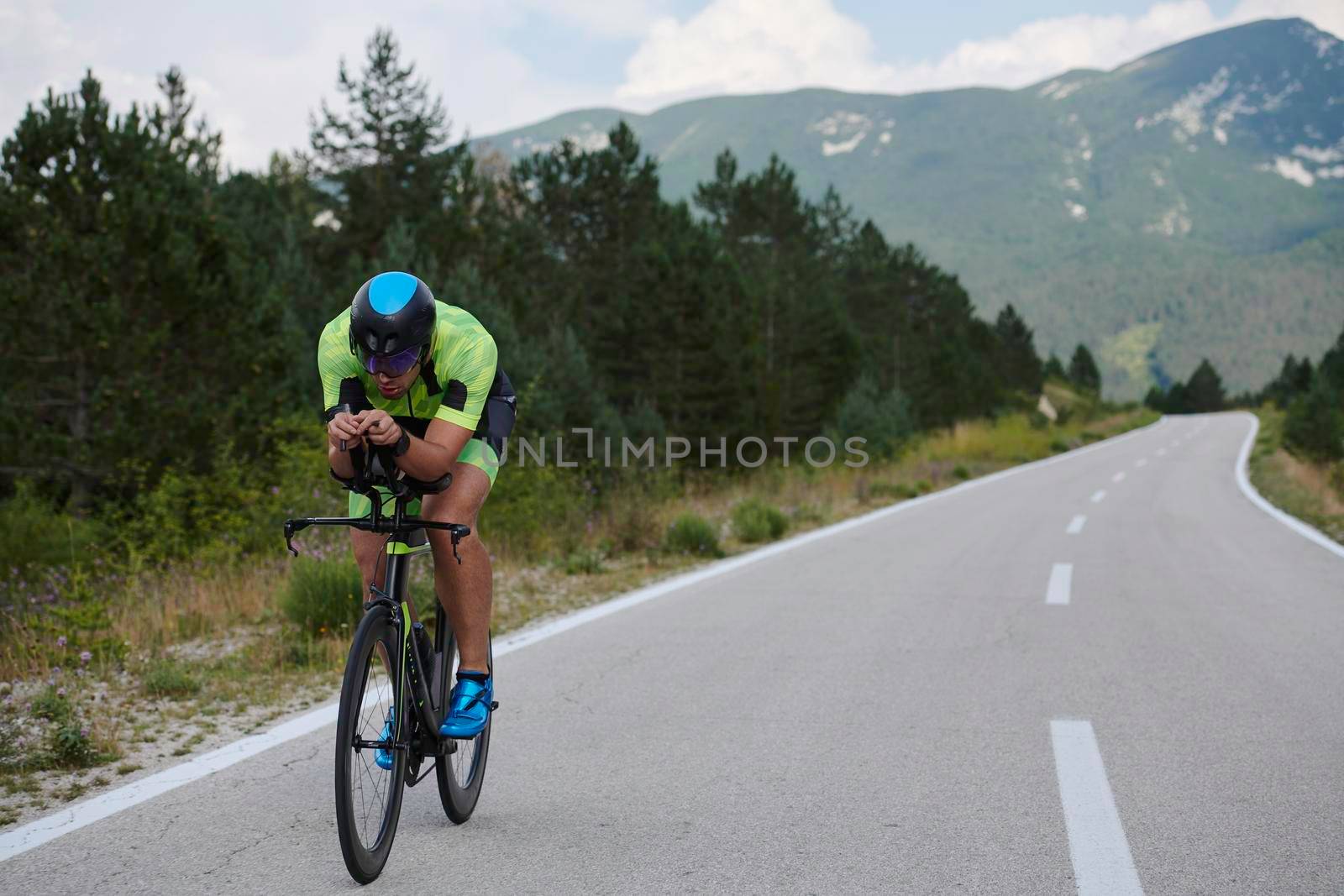 triathlon athlete riding professional racing bike at workout on curvy country road