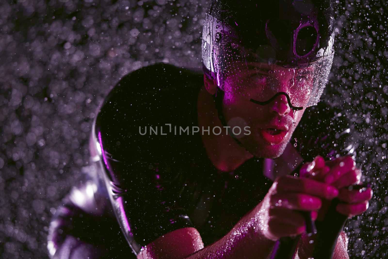 triathlon athlete riding bike  fast on rainy night by dotshock