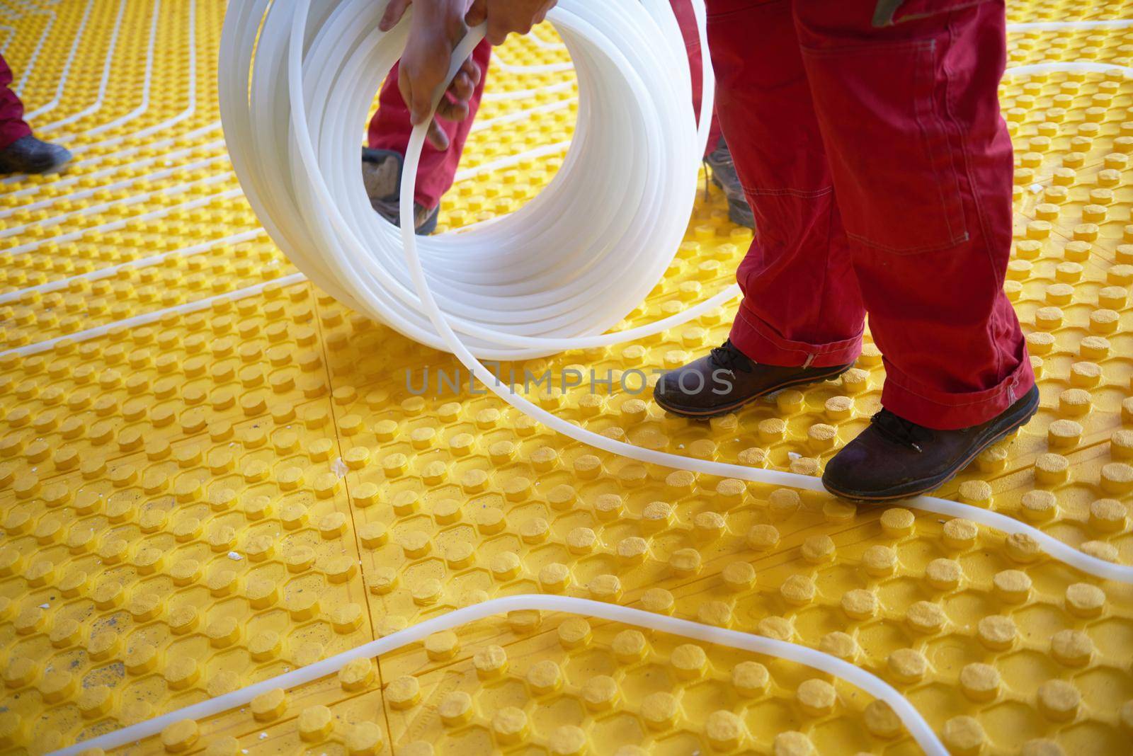 workers installing underfloor heating system by dotshock