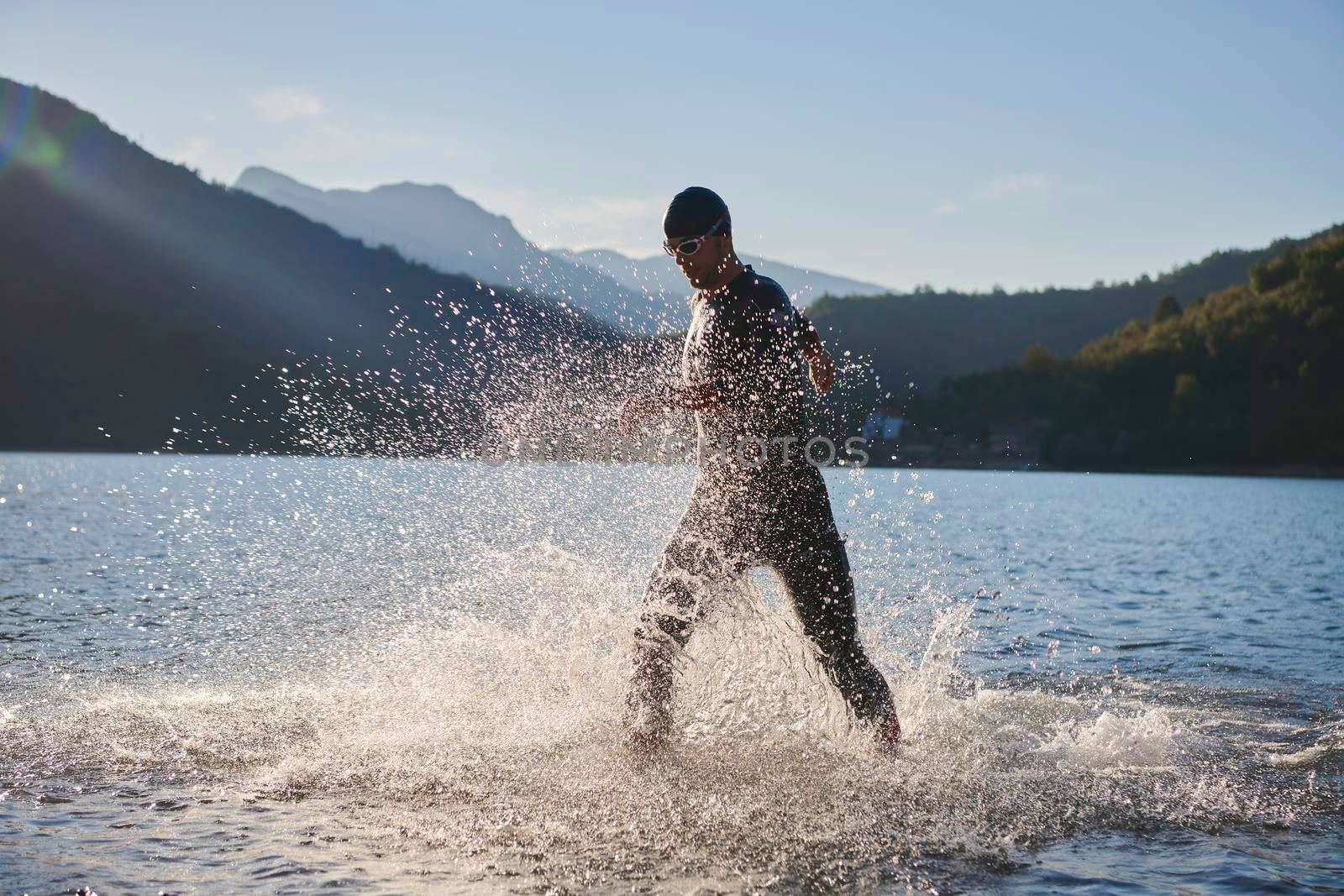 triathlon athlete start swimming training splashing water while running and jumping