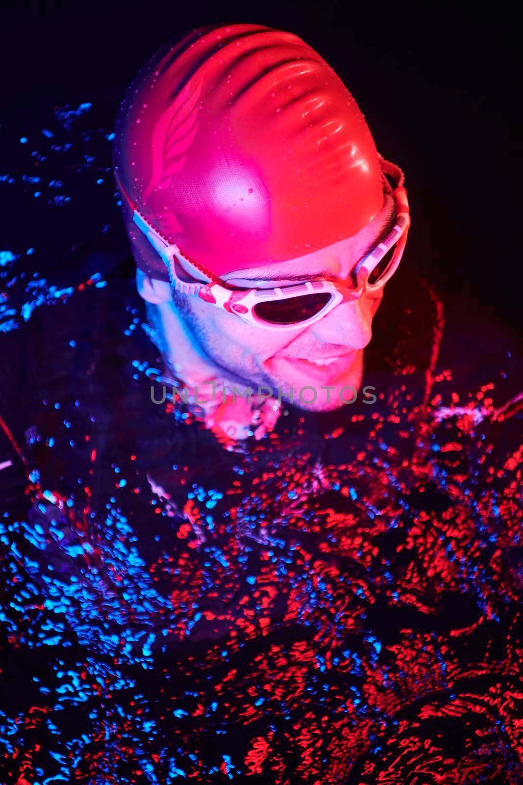 authentic triathlete swimmer having a break during hard training on night neon gel light by dotshock