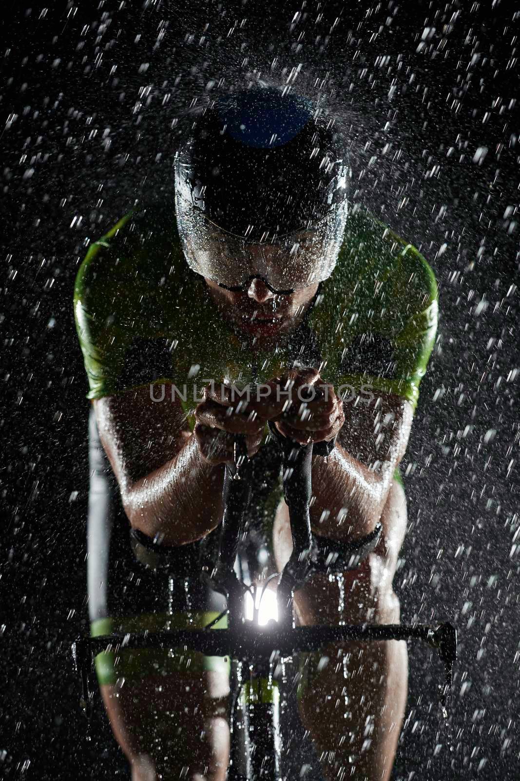 triathlon athlete riding professional racing bike fast  at night with bad weather and falling rain