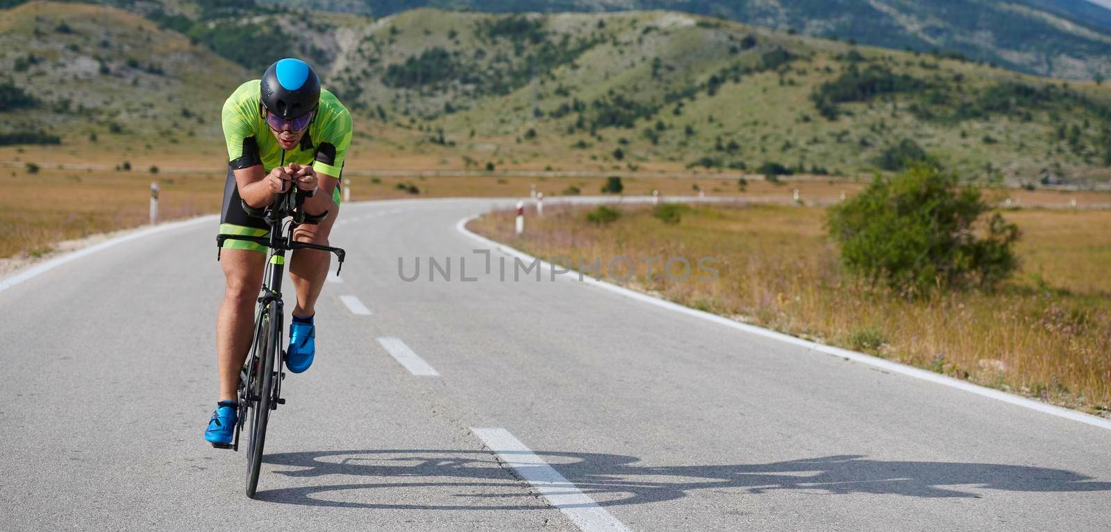 triathlon athlete riding professional racing bike at workout on curvy country road