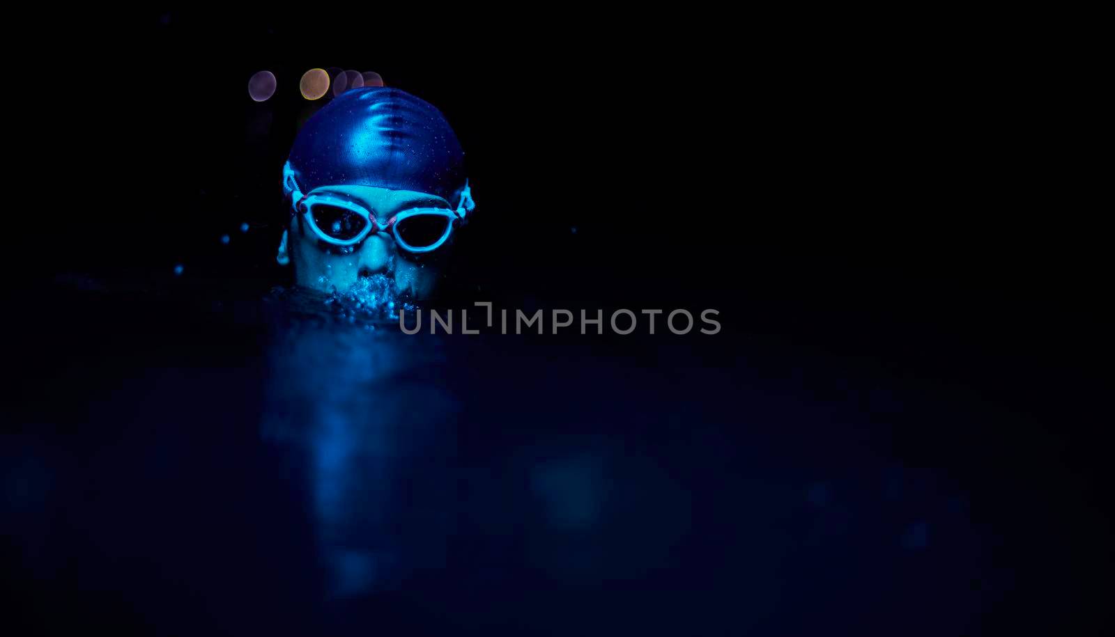 real triathlete swimmer having a break during hard training at lake on dark night neon gel color lights